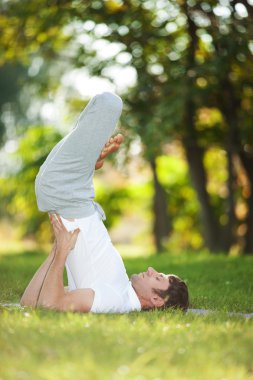 Adam parkta yoga egzersizleri yapıyor.