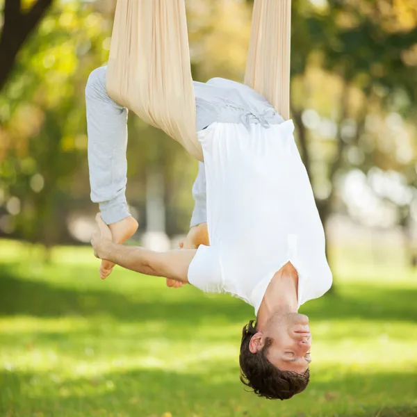 Anti-zwaartekracht yoga, man doen yoga oefeningen in het park — Stockfoto