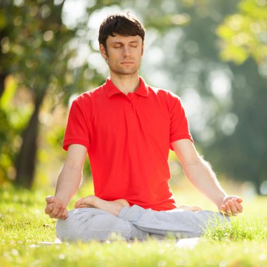 Adam parkta yoga egzersizleri yapıyor.