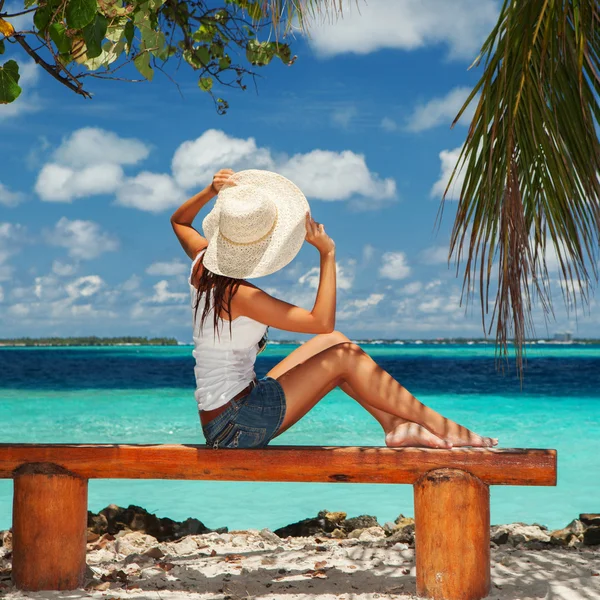 Modefrau sitzt auf einer Bank am Strand — Stockfoto