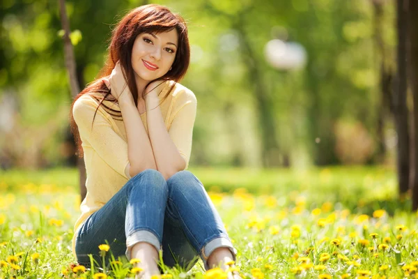 Młoda kobieta w parku z kwiatami — Zdjęcie stockowe