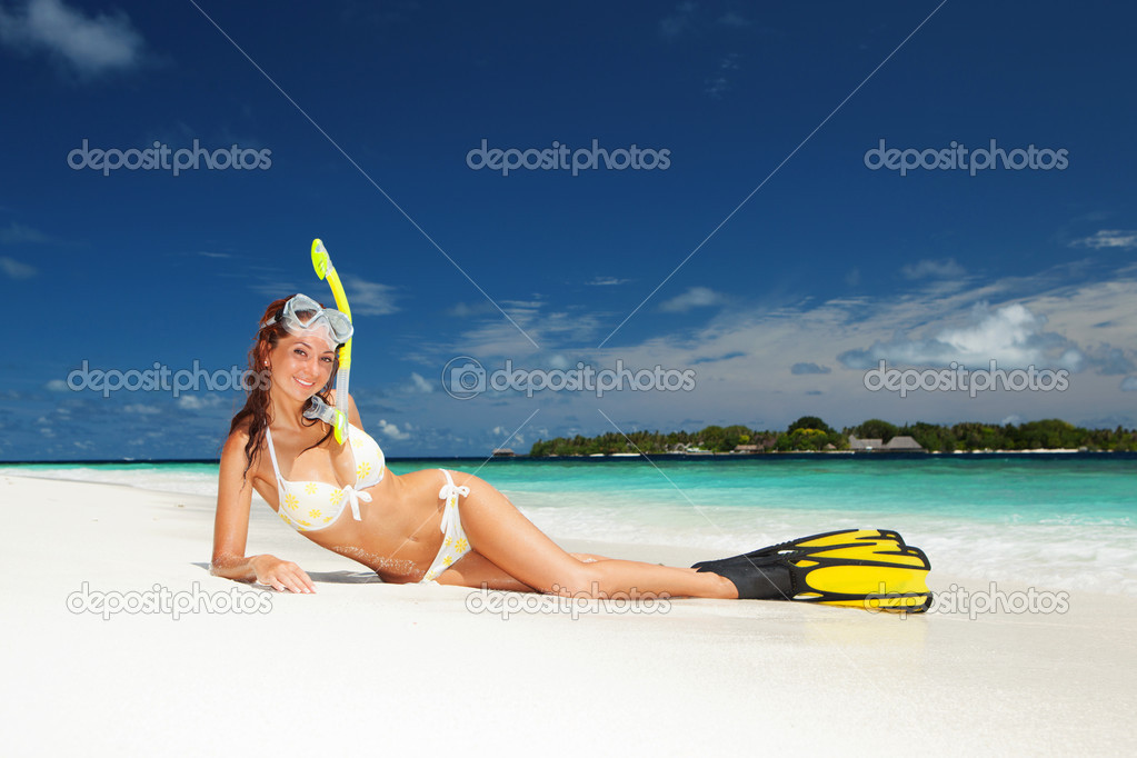 Cute woman with snorkeling equipment relaxing on the tropical be