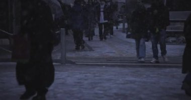 Shinjuku Tokyo 'da şehir caddesinde yürüyen insanlar el kamerasıyla kar yağıyor.