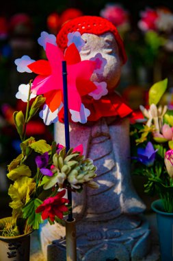 Heykel bekçisi kırmızı şapka takıyor. Tokyo Minato Bölgesi - 07.25.2019: Geleneksel tapınakta bulunan eski bir heykel.