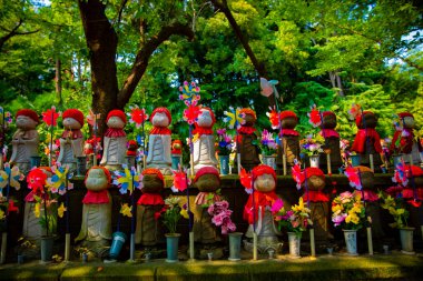 Heykel bekçisi kırmızı şapka takıyor. Tokyo Minato Bölgesi - 07.25.2019: Geleneksel tapınakta bulunan eski bir heykel.