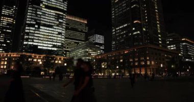 Tokyo 'daki iş kasabasında yürüyen insanların olduğu bir gece manzarası.