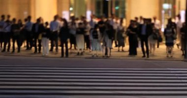 Tokyo 'daki iş kasabasında yürüyen insanların gece manzarası.
