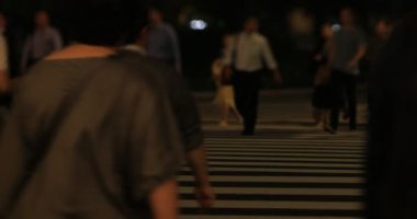 Tokyo 'daki iş kasabasında yürüyen insanların gece manzarası.