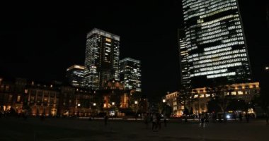 Tokyo 'daki iş kasabasında yürüyen insanların olduğu bir gece manzarası.