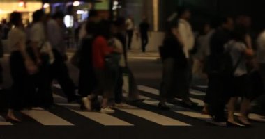 Tokyo 'daki iş kasabasında yürüyen insanların gece manzarası.