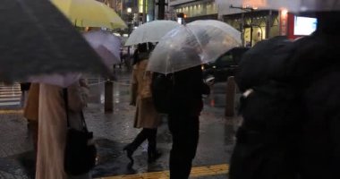 Tokyo yağmurlu bir günde Shibuya geçişinde yürüyüş insanlar