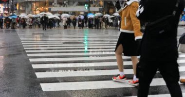 Tokyo yağmurlu bir günde Shibuya geçişinde yürüyüş insanlar