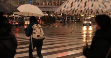Tokyo yağmurlu bir günde Shibuya geçişinde yürüyüş insanlar