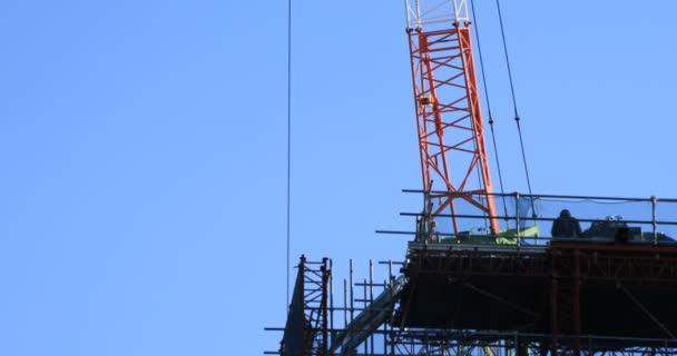 Grúas móviles detrás del cielo azul en la construcción bajo — Vídeos de Stock