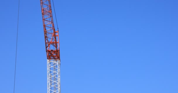 Bewegende kranen achter de blauwe lucht bij de aanbouw — Stockvideo