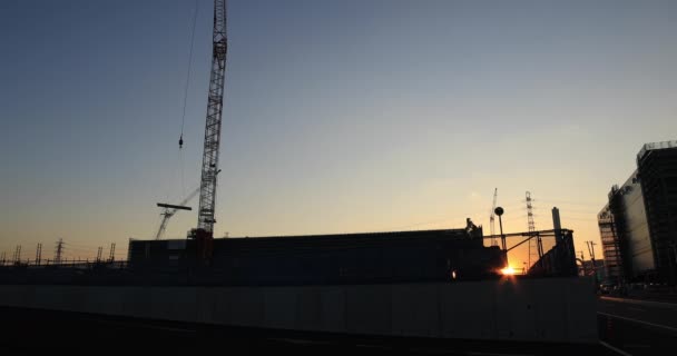 Guindastes em movimento atrás do céu azul no sob construção crepúsculo tiro largo — Vídeo de Stock