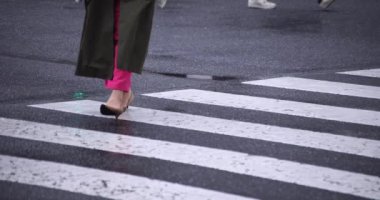 Shibuya 'da yağmurlu bir günde geçitte yürüyen insanların ağır çekimleri.