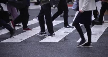 Shibuya 'da yağmurlu bir günde geçitte yürüyen insanların ağır çekimleri.