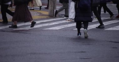 Shibuya 'da yağmurlu bir günde geçitte yürüyen insanların ağır çekimleri.