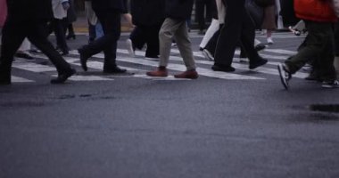 Shibuya 'da yağmurlu bir günde geçitte yürüyen insanların ağır çekimleri.