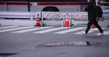Shibuya 'da yağmurlu bir günde geçitte yürüyen insanların ağır çekimleri.