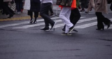 Shibuya 'da yağmurlu bir günde geçitte yürüyen insanların ağır çekimleri.