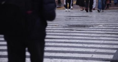 Shibuya 'da yağmurlu bir günde geçitte yürüyen insanların ağır çekimleri.