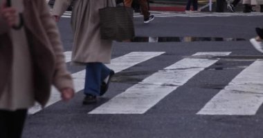 Shibuya 'da yağmurlu bir günde geçitte yürüyen insanların ağır çekimleri.