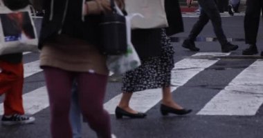 Shibuya 'da yağmurlu bir günde geçitte yürüyen insanların ağır çekimleri.