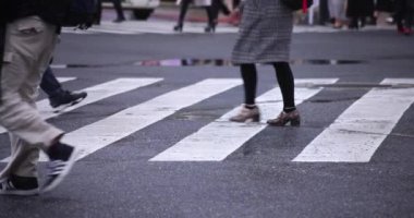 Shibuya 'da yağmurlu bir günde geçitte yürüyen insanların ağır çekimleri.