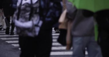 Shibuya 'da yağmurlu bir günde geçitte yürüyen insanların ağır çekimleri.