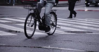 Shibuya 'da yağmurlu bir günde geçitte yürüyen insanların ağır çekimleri.