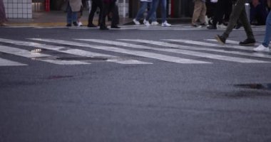 Shibuya 'da yağmurlu bir günde geçitte yürüyen insanların ağır çekimleri.