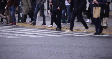 Shibuya 'da yağmurlu bir günde geçitte yürüyen insanların ağır çekimleri.