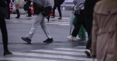 Shibuya 'da yağmurlu bir günde geçitte yürüyen insanların ağır çekimleri.