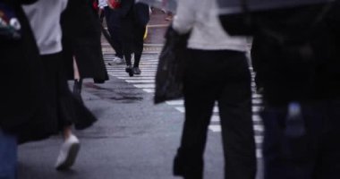 Shibuya 'da yağmurlu bir günde geçitte yürüyen insanların ağır çekimleri.