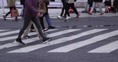 Shibuya 'da yağmurlu bir günde geçitte yürüyen insanların ağır çekimleri.