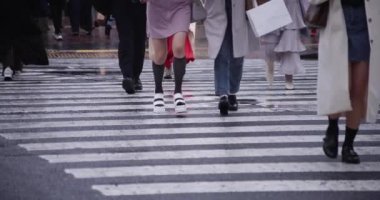 Shibuya 'da yağmurlu bir günde geçitte yürüyen insanların ağır çekimleri.