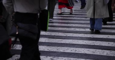 Shibuya 'da yağmurlu bir günde geçitte yürüyen insanların ağır çekimleri.