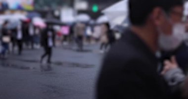 Shibuya 'da yağmurlu bir günde geçitte yürüyen insanların ağır çekimleri.
