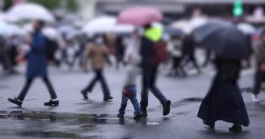 Shibuya 'da yağmurlu bir günde geçitte yürüyen insanların ağır çekimleri.