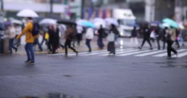 Shibuya 'da yağmurlu bir günde geçitte yürüyen insanların ağır çekimleri.
