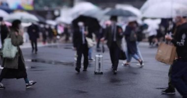 Shibuya 'da yağmurlu bir günde geçitte yürüyen insanların ağır çekimleri.