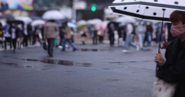 Shibuya 'da yağmurlu bir günde geçitte yürüyen insanların ağır çekimleri.