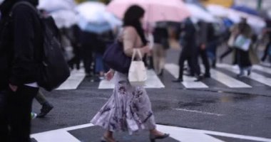 Shibuya 'da yağmurlu bir günde geçitte yürüyen insanların ağır çekimleri.