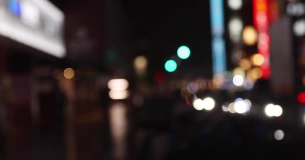 Defocused walking people on the street in Shinjuku at night rainy day handheld — Stockvideo