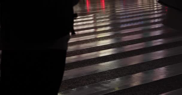 Body parts of walking people on the street in Shinjuku at night rainy day handheld — стоковое видео