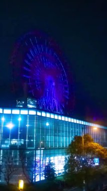 Gece dikey çekimde nehir kenarındaki dönme dolap. Koutou-ku Odaiba Tokyo Japonya - 12.18.2018: Gece dönme dolap. 4K zaman aşımı. Kamera: Canon EOS 5D işaret 4