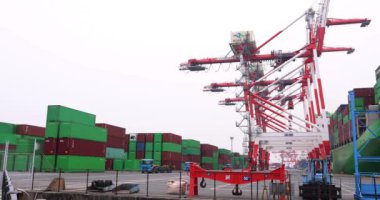 Industrial cranes and a large ship near the container wharf cloudy day wide shot. High quality 4k footage. Koto district Aomi Tokyo Japan 05.20.2022 Here is called Aomi Container Wharf. It is one of