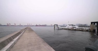 Tokyo 'daki konteynır iskelesinin yanında büyük bir gemi. Bulutlu bir gün olacak. Koto bölgesi Aomi Tokyo Japonya 05.20.2022 Burası Aomi Konteynır Rıhtımı. Limandaki konteynır iskelelerinden biri.